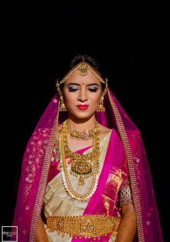 Photo of Bride in white and pink wearing south indian temple jewellery