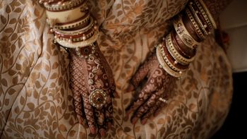 Photo of An alluring shot of a bride with a unique chooda and gold haathphool.