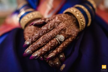 bridal hands with maroon manicure and engagement ring 