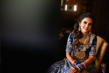 bride wearing a choker and pearl rani haar with a blue lehenga