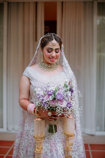 Photo of simple bridal look with bride holding a purple bouquet