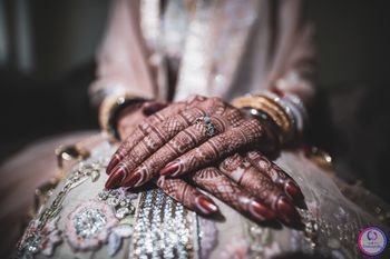 beautiful bridal hands with mehendi and maroon manicure 