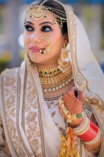 Photo of A beautiful bride in white lehenga and gold jewellery.