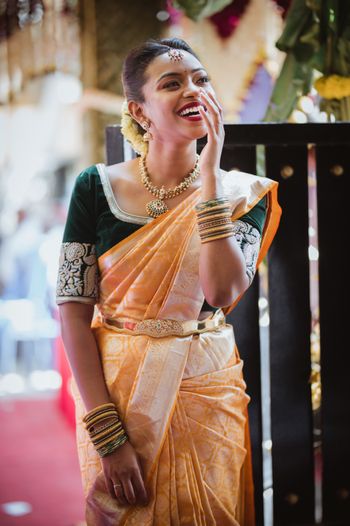 South Indian bride wearing a yellow saree with an emerald green blouse