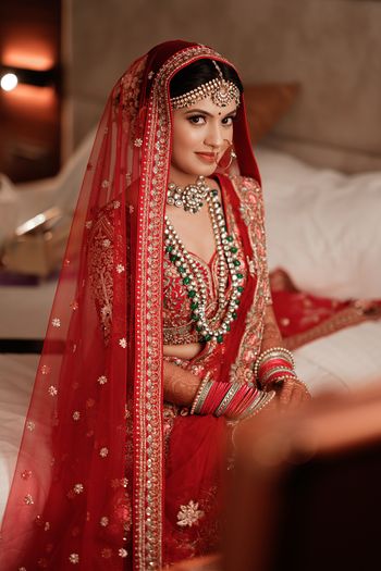 Photo of Bride in red lehenga posing on her wedding day.