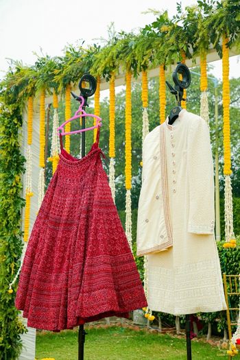 Photo of lehenga and sherwani on hanger next to each other