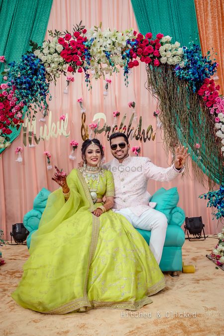 Mehendi couple portrait against floral arch