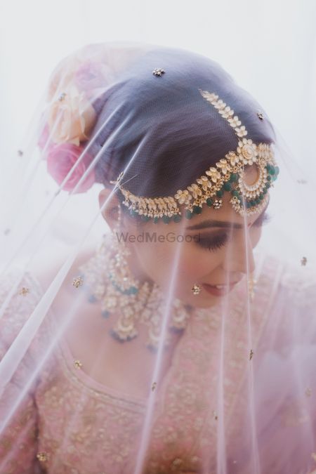 A glamorous bridal shot under dupatta as veil. 