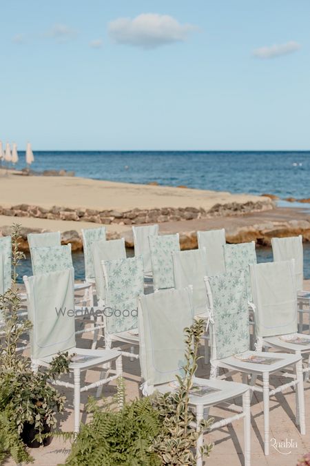 Photo of Stunning beach wedding venue with white and printed chair decor for guests