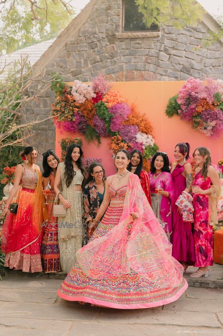 Lovely colourful mehendi shot with the bride twirling in her lehenga with bridesmaids