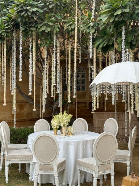 Stunning all-white decor with hanging florals and white umbrellas for an outdoor event