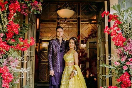 groom in purple indo western and bride in yellow lehenga for mehendi ceremony