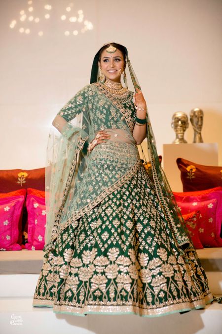 A bride in green and gold lehenga for her wedding