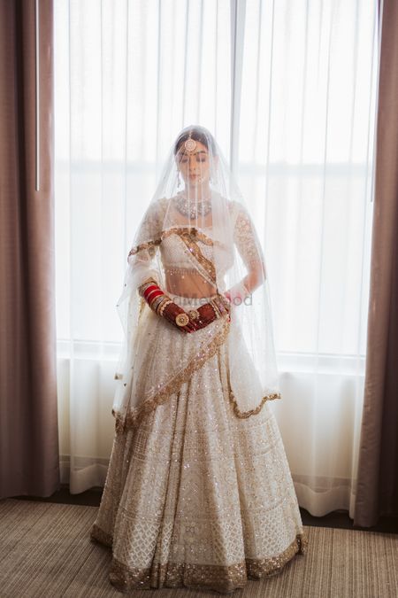 Photo of light bridal lehenga in ivory and white with dupatta as veil