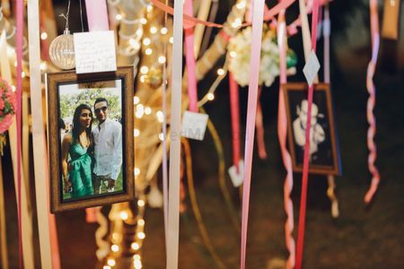 Couple photos hung from tree with ribbons. Guest leave wishes