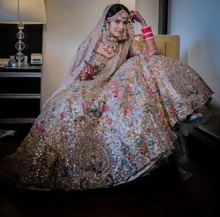 A gorgeous bridal pose shot, focusing on the details of the bridal lehenga 