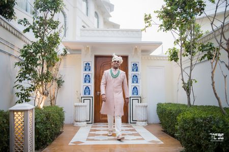 A groom in a pink sherwani and contrasting green accessories 