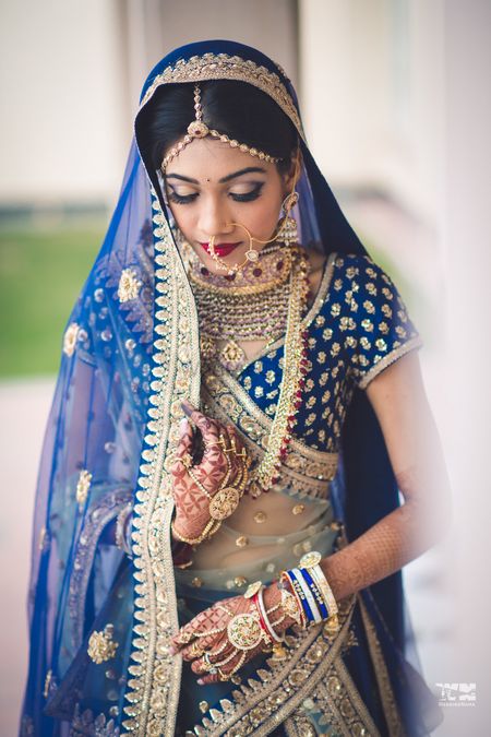 Photo of Bride in offbeat blue lehenga and gold jewellery