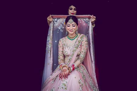 Photo of A bride gets ready as her sister drapes a dupatta over hear head