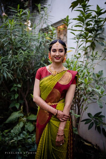Bride wearing a green and maroon saree with temple jewellery.
