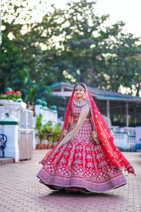 Bride twirling in a red lehenga with contrasting lighter dupatta