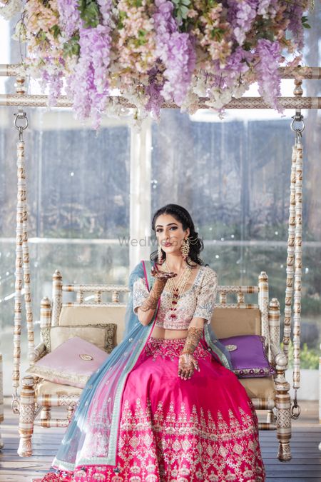 Photo of Bride wearing a pink and white lehenga with a blue dupatta on mehndi.
