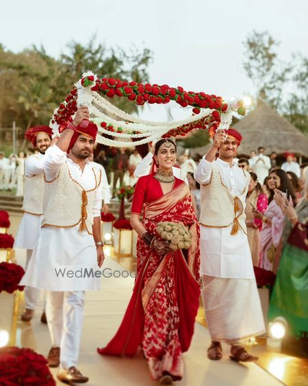 Photo of Bridal entry under phoolon ki chaddar adorned with red roses and the bride in a red sabyasachi saree