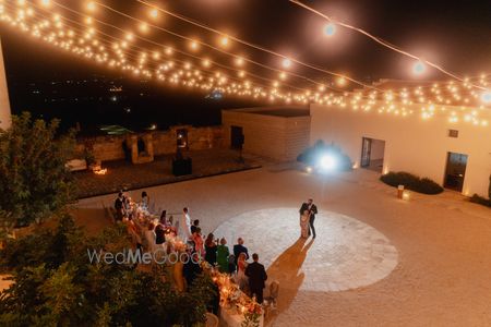 Lovely shot of the bride and groom dancing under a canopy of lights at an outdoor reception