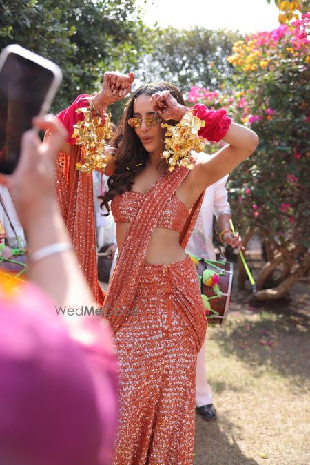 Super stylish orange saree with sequin work in a pre-draped style for her chooda ceremony