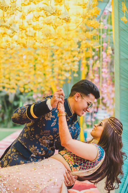 Photo of Mehendi couple portrait idea against yellow floral strings