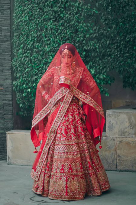 red sabyasachi bridal lehenga with dupatta as veil