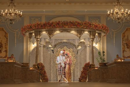 couple pose against grand south indian gold mandap