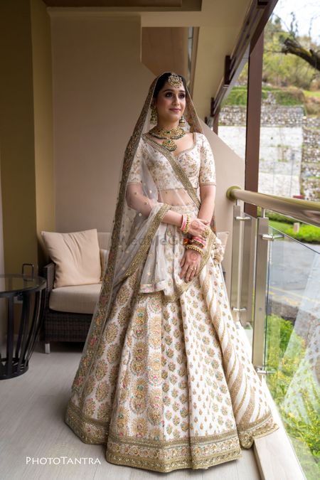Photo of A bride in an ivory and gold lehenga with contrasting jewellery