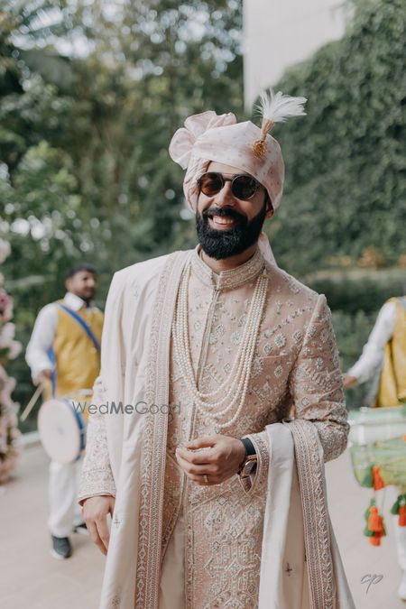 Unique peach sherwani with pearl jewellery for the groom to be on his wedding day