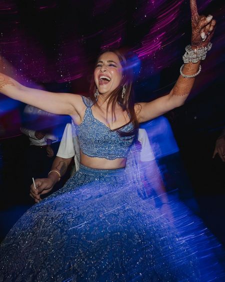 Super fun twirling shot of the bride in a cerulean blue lehenga and statement diamond bracelets