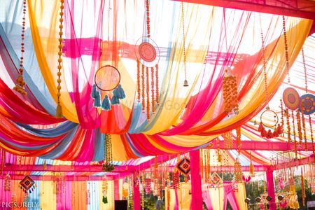 Mehendi decor idea with dreamcatchers hanging on tent drapes