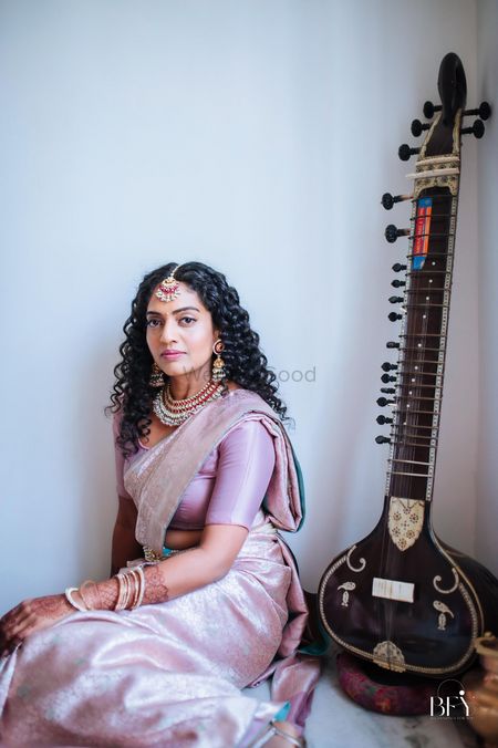 south indian bride in pink saree posing with sitar