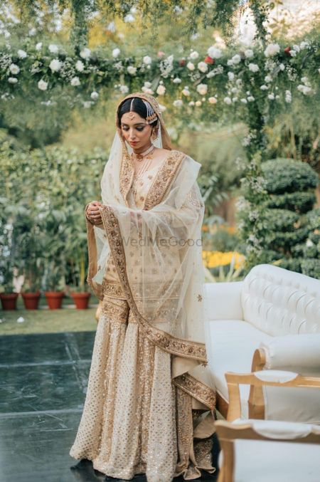 Bride wearing a white and gold sharara set on her wedding day.