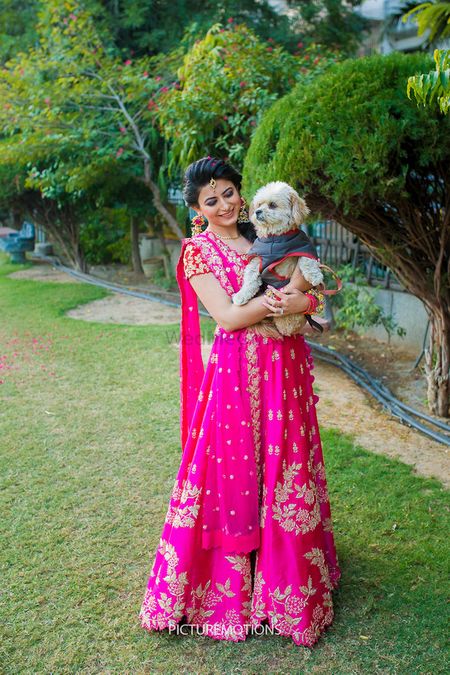 Photo of Bride in bright pink lehenga with dog