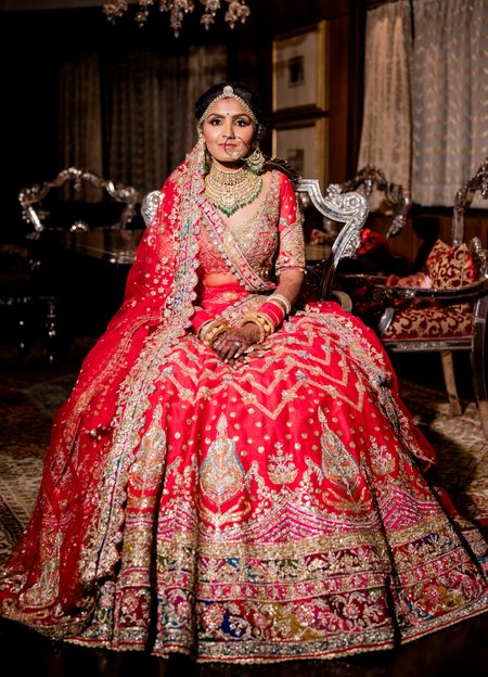 A bridal portrait captured with the bride in a bright pink and red ombre lehenga 