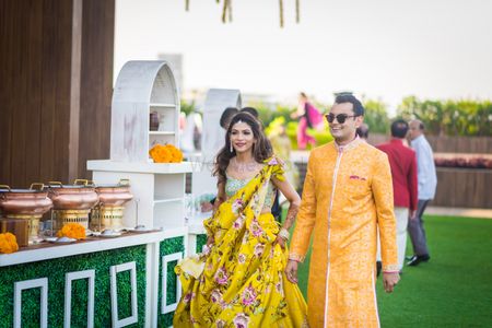 A bride and groom to be in yellow at their mehendi function