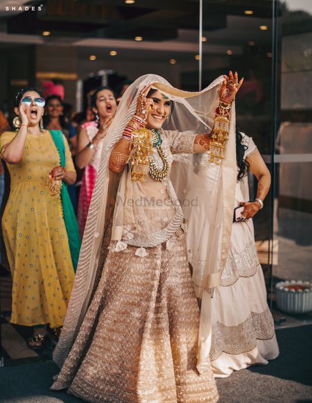 Photo of A mischevious bride entering in a white and gold lehenga for her Anand Karaj