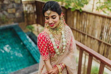 Photo of Unique simple bridal look in red blouse and layered jewellery