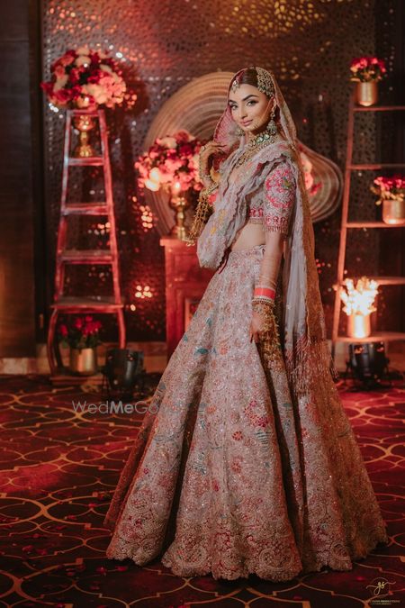 Photo of Classic bridal portrait with the bride in a light pink and red lehenga with heavy work