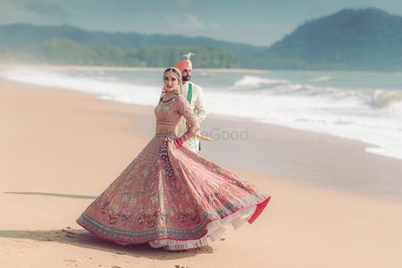 Photo of Twirling bride and the groom on the beach on their wedding day