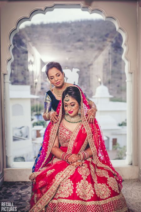 Brides mom placing the red dupatta on her head