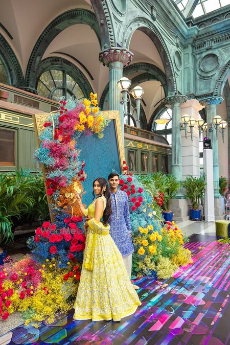Photo of Gorgeous multi coloured floral decor with the bride in a yellow lehenga for the wedding