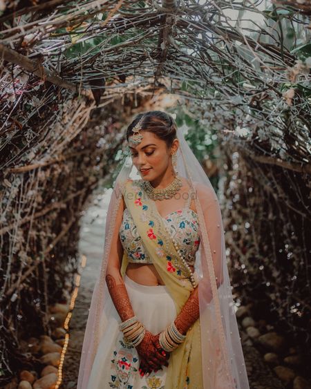 Bride wearing an ivory lehenga with double dupattas.