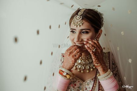 Photo of under the veil shot with bride adjusting her nosering