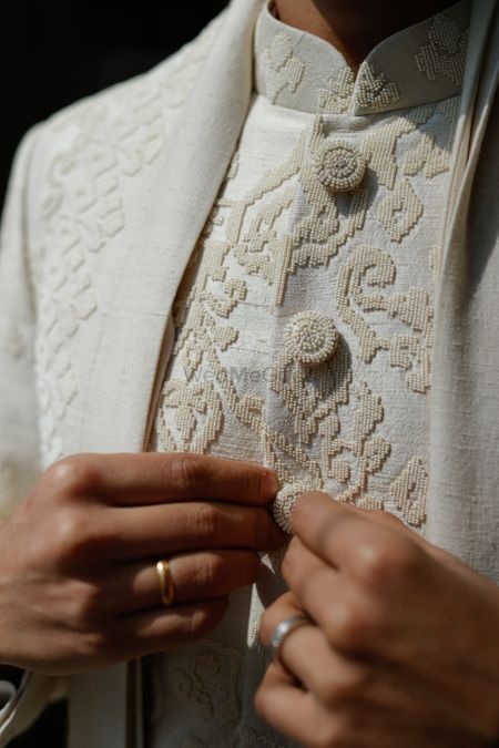 Gorgeous close up shot of the intricate pearl embroidery for the groom sherwani in ivory. 